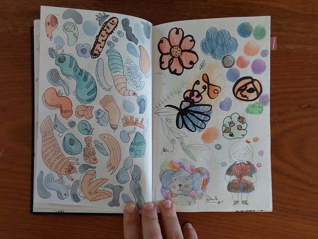 Caderno aberto com desenhos coloridos diversos